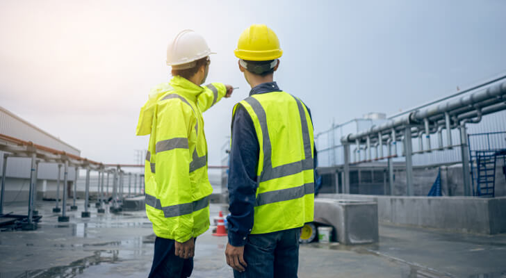 Two professionals wearing hard hats and reflective vests