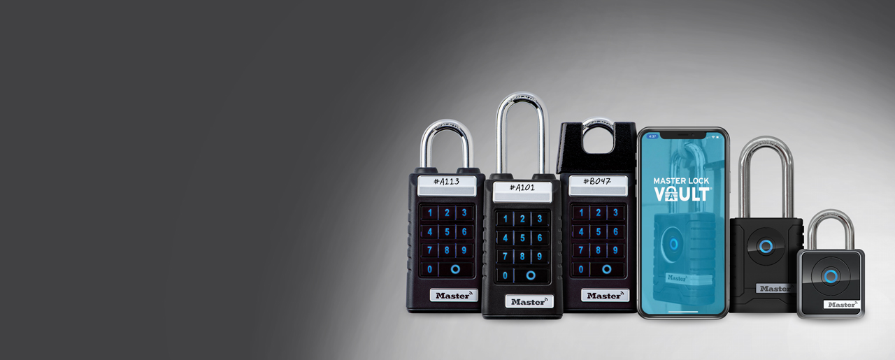 A collection of Bluetooth enabled hardware alongside a phone showing the Master Lock Vault Enterprise app