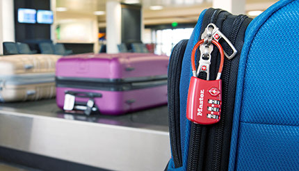 A piece of luggage at an airport baggage claim secured with a combination padlock